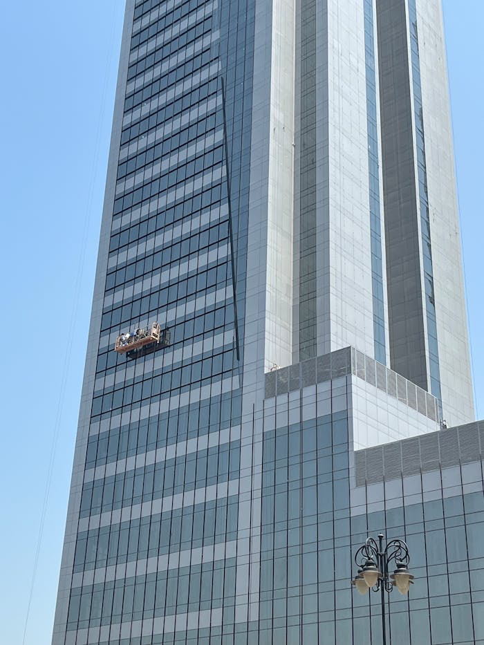 High-rise skyscraper with a glass facade reflecting the bright daylight in an urban cityscape.